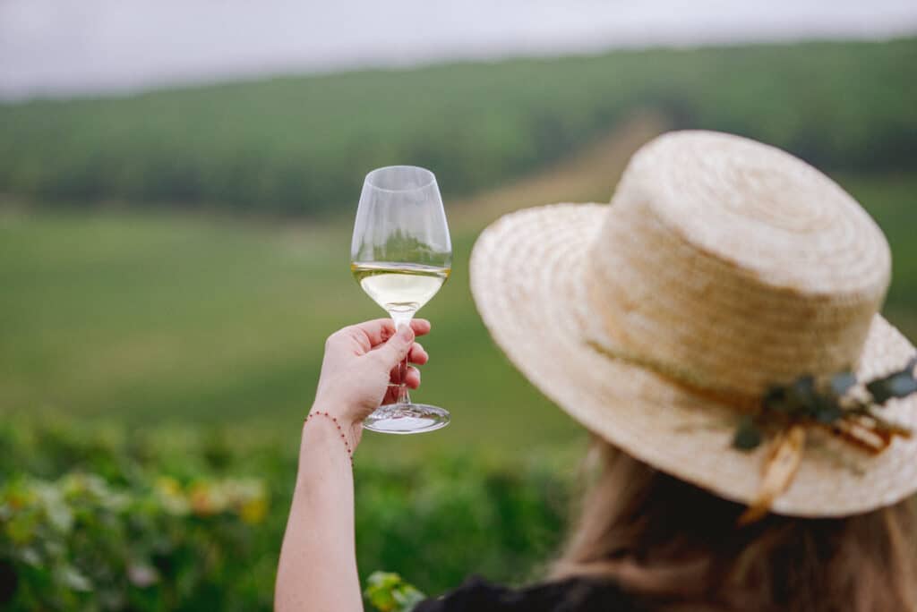Balade à vélo dans les vignes à Chablis : femme tenant un verre de vin dans les vignes à Chablis, lors d’une expérience œnotouristique proposée par Laroche.